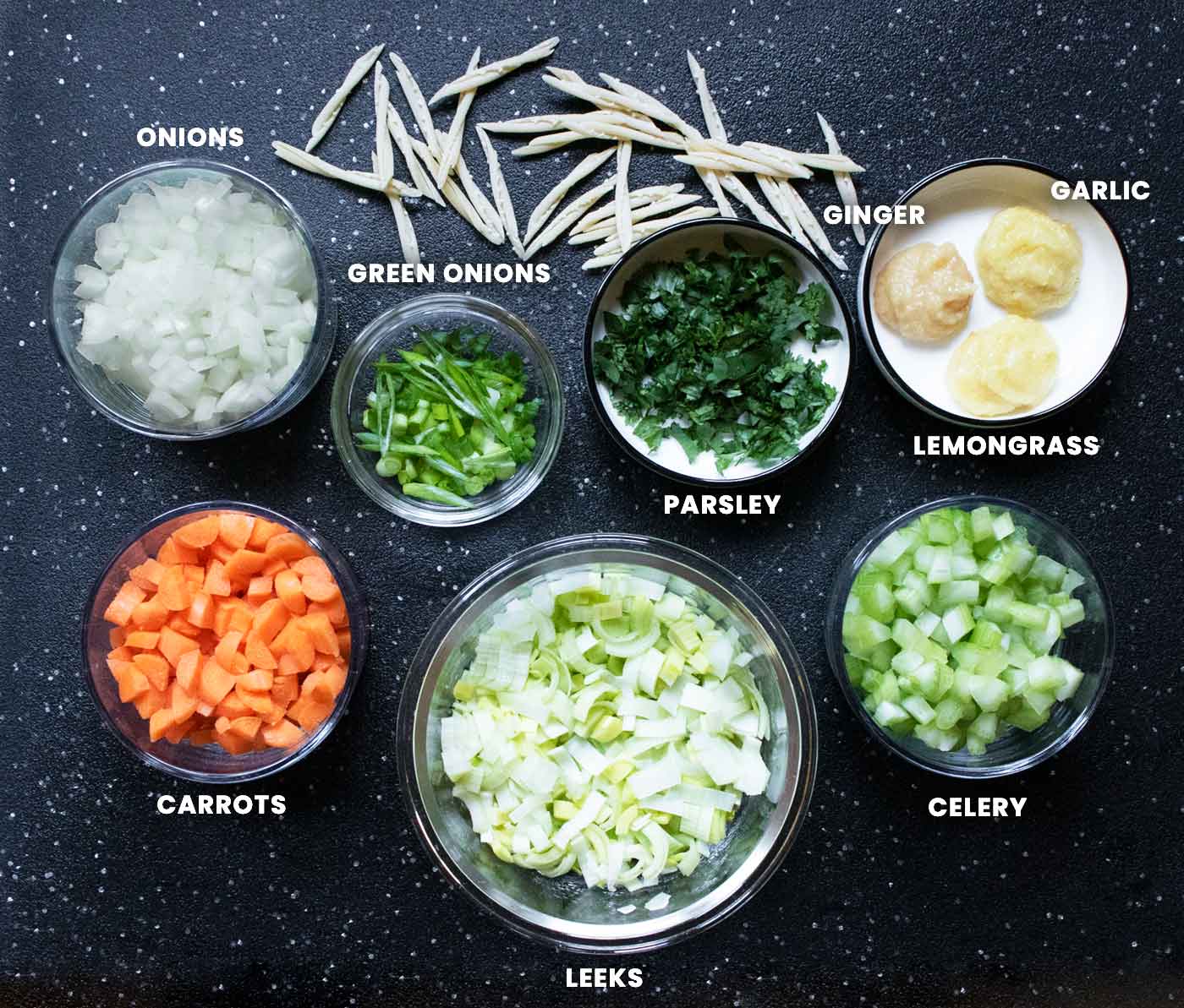 Prepared ingredients for the soup, arranged in pinch bowls on a black cutting board.