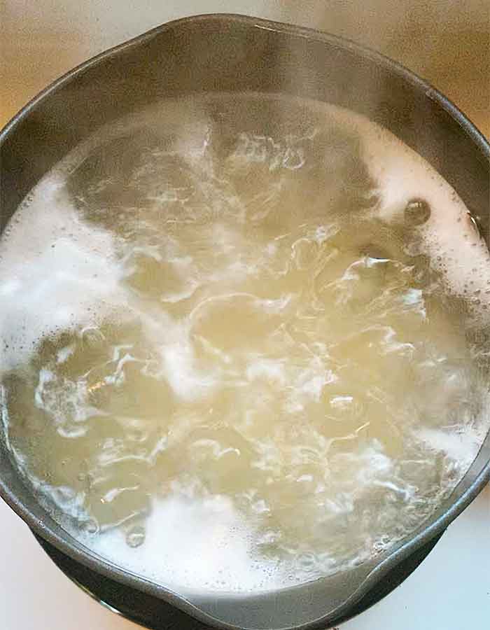 Pasta in boiling water in a black pot.