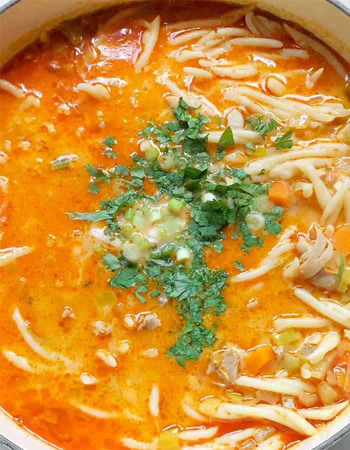 Topping the soup with minced fresh cilantro leaves and green onion slices.