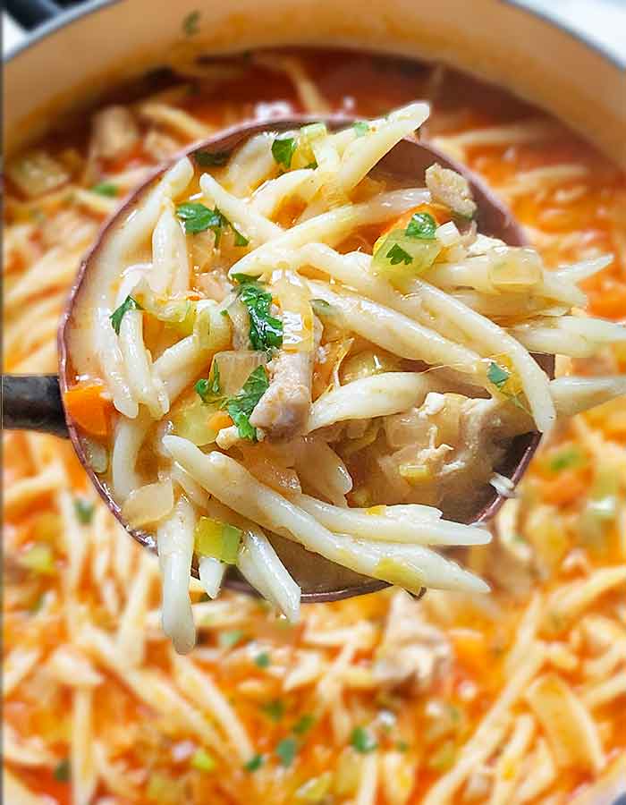 Close-up of a copper ladle with a scoop full of soup.