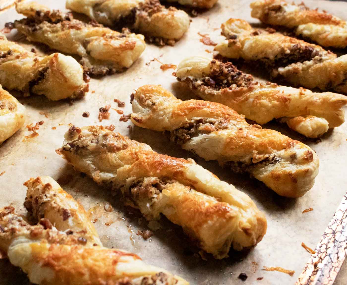 Side-angled view of a baking sheet full of Cheesy Candied Bacon Twists, fresh from the oven.