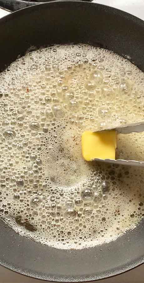 A pat of butter melting in the rendered bacon fat.