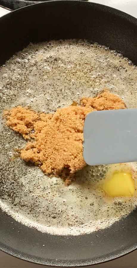 Stirring the brown sugar into the hot fats with a gray silicone spurtle.