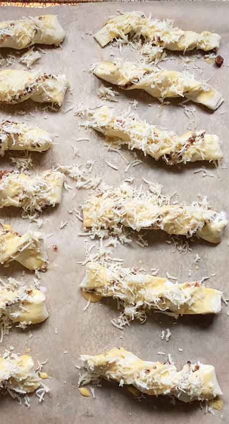 Topping the twists with shredded cheese.
