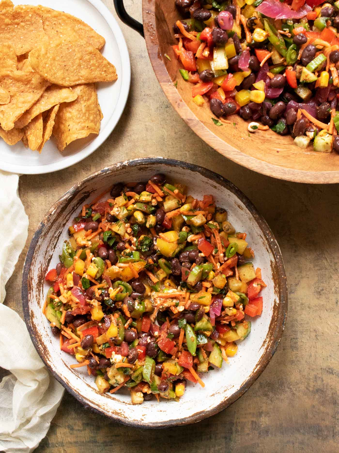 The mixing bowl with the salad, the serving bowl, and a plate of sweet potato tortilla chips.