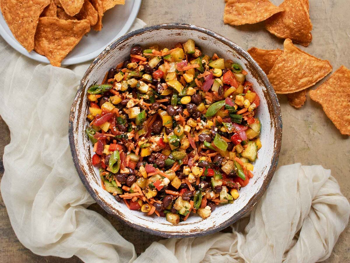 Overhead view of a bowl of Eat Your Veggies Salad with a side of sweet potato tortilla chips.