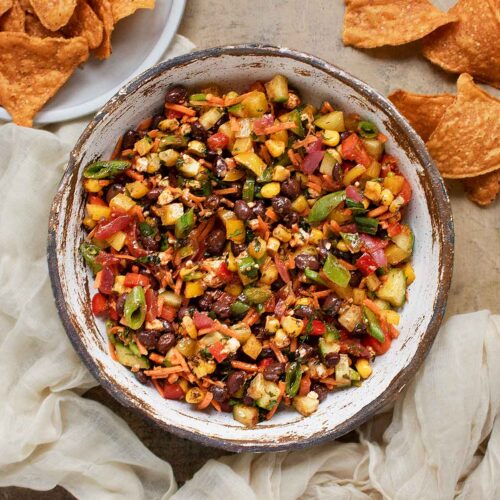 Overhead view of a bowl of Eat Your Veggies Salad with a side of sweet potato tortilla chips.