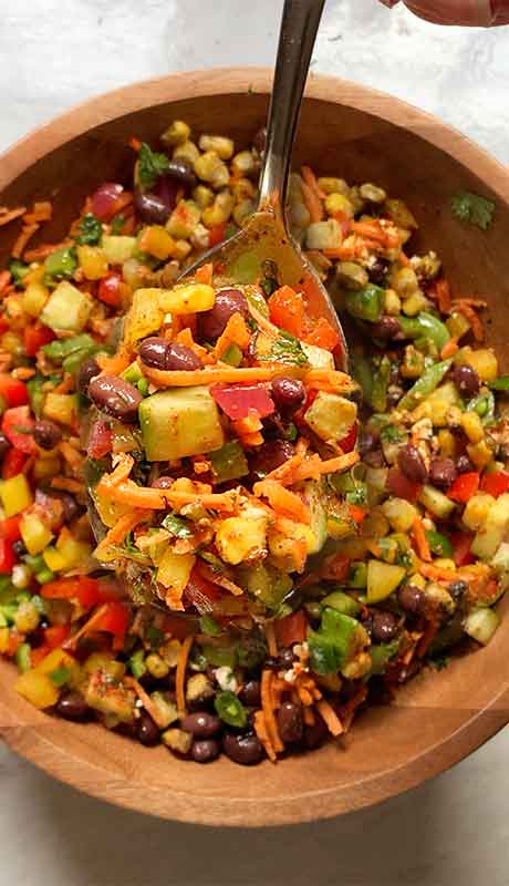 Ready to serve - a large serving spoon filled with salad.