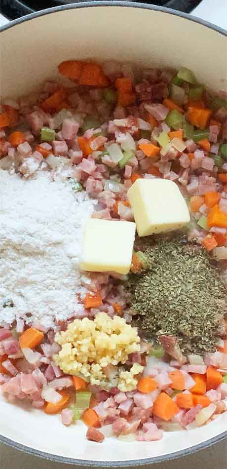 Adding flour, butter and seasonings to the pork and vegetable mix.