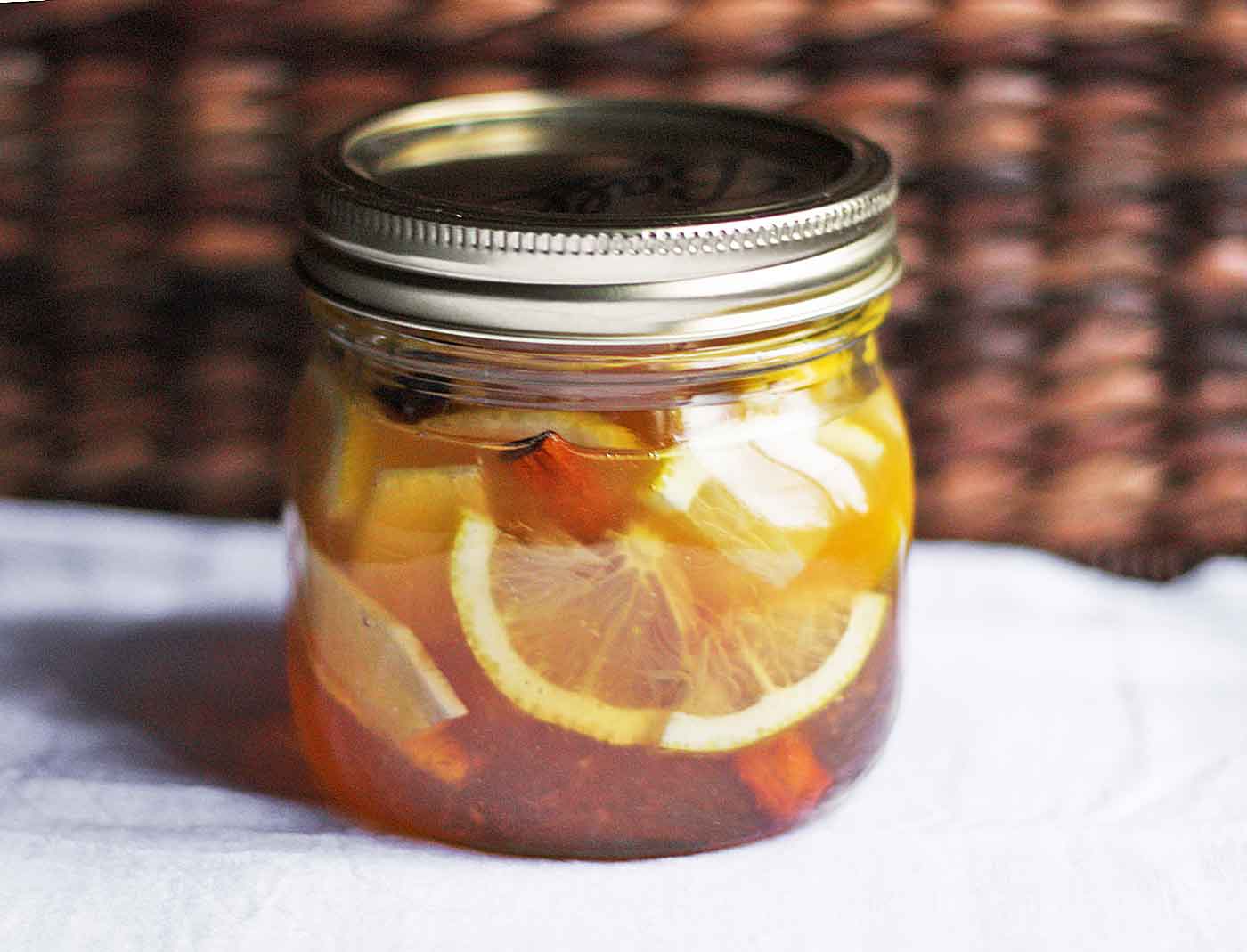A mason jar of Soothing Cold Elixir sitting on a white cloth.