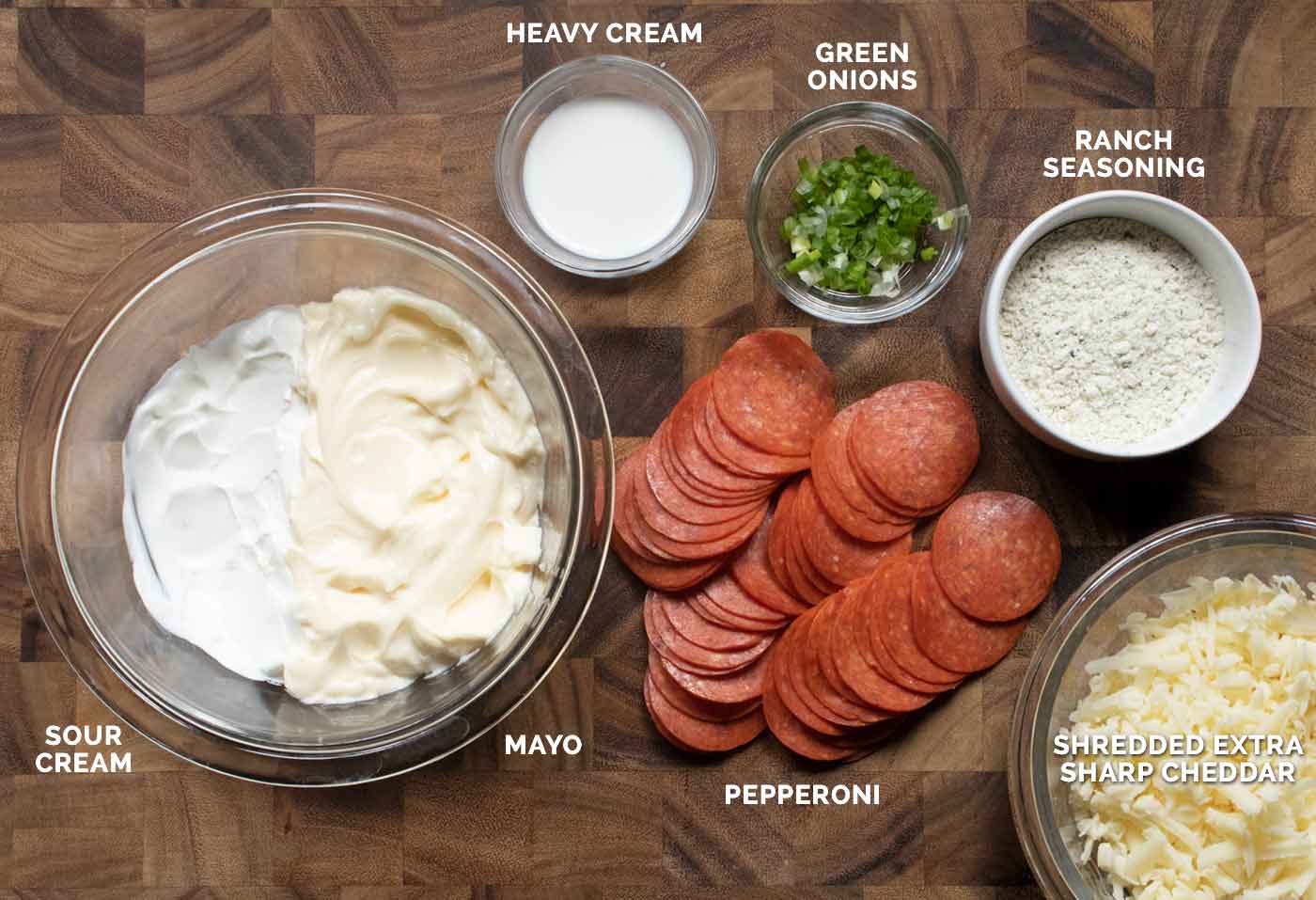 Ingredients for the dip prepped and arranged on a wooden board in serving bowls.