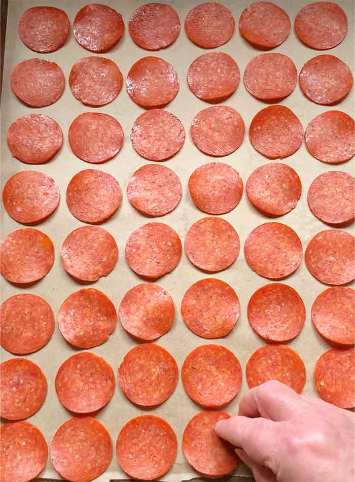 Lining up the pepperoni slices on a large sheet pan.