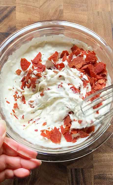 Stirring the chopped pepperonis into the dip.