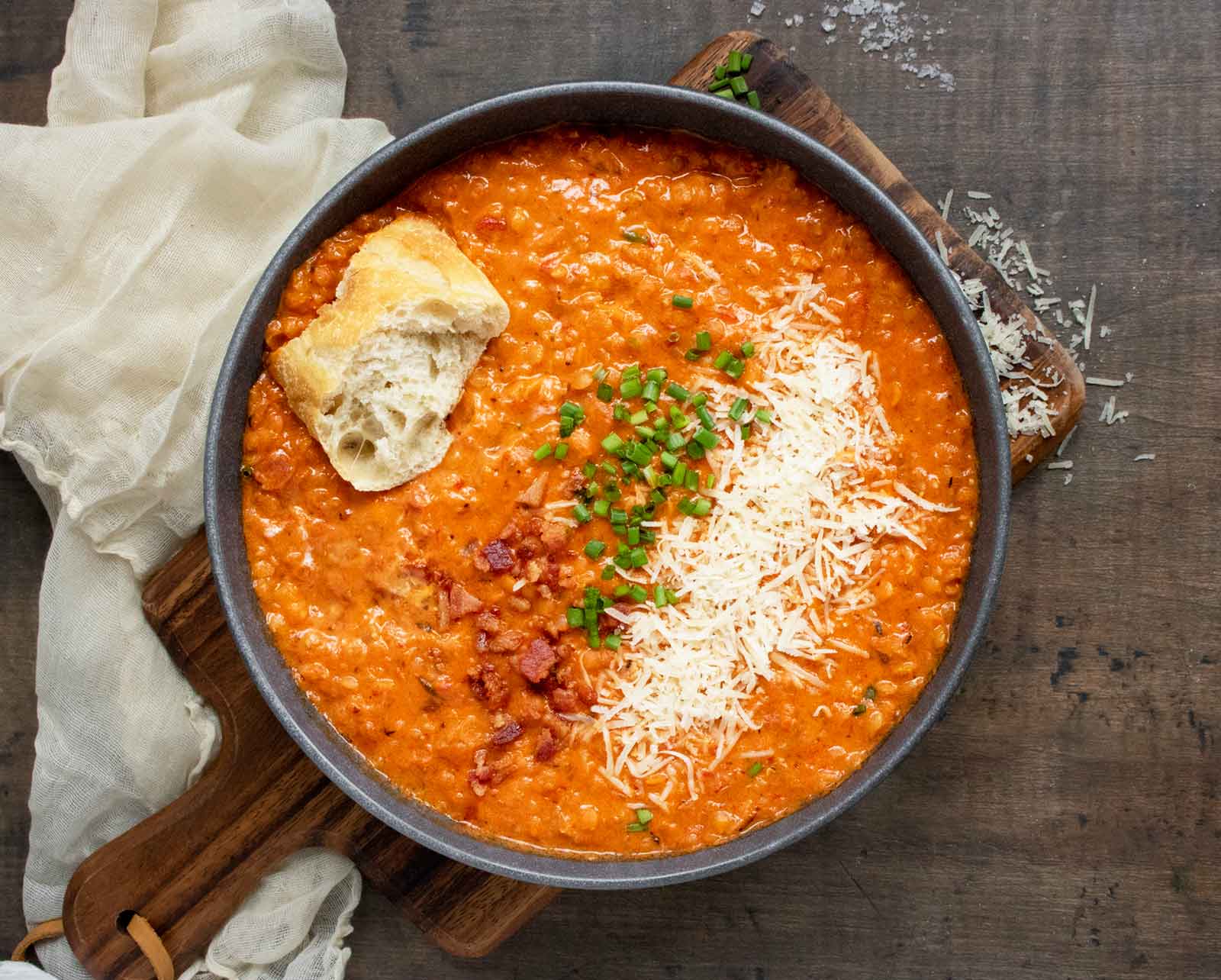 Overhead view of Marry Me Red Lentil Soup in a bowl with a chunk of bread.