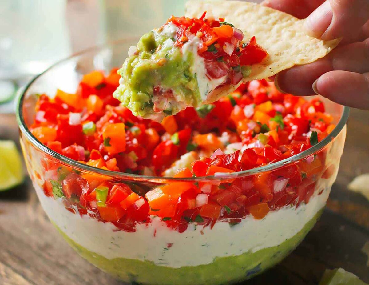 Triple Layer Guacamole Dip in a tortilla chip.