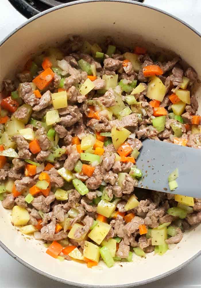 Aromatic vegetables cooking in the pot with the beef.