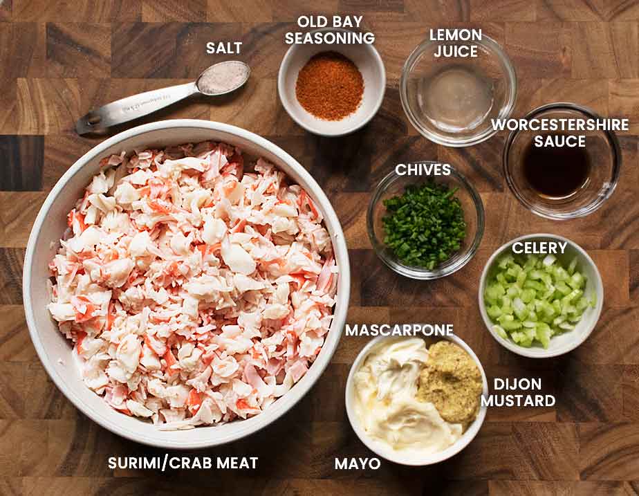 Ingredients for the crab salad measured into bowls and arranged on a board, with text labels.