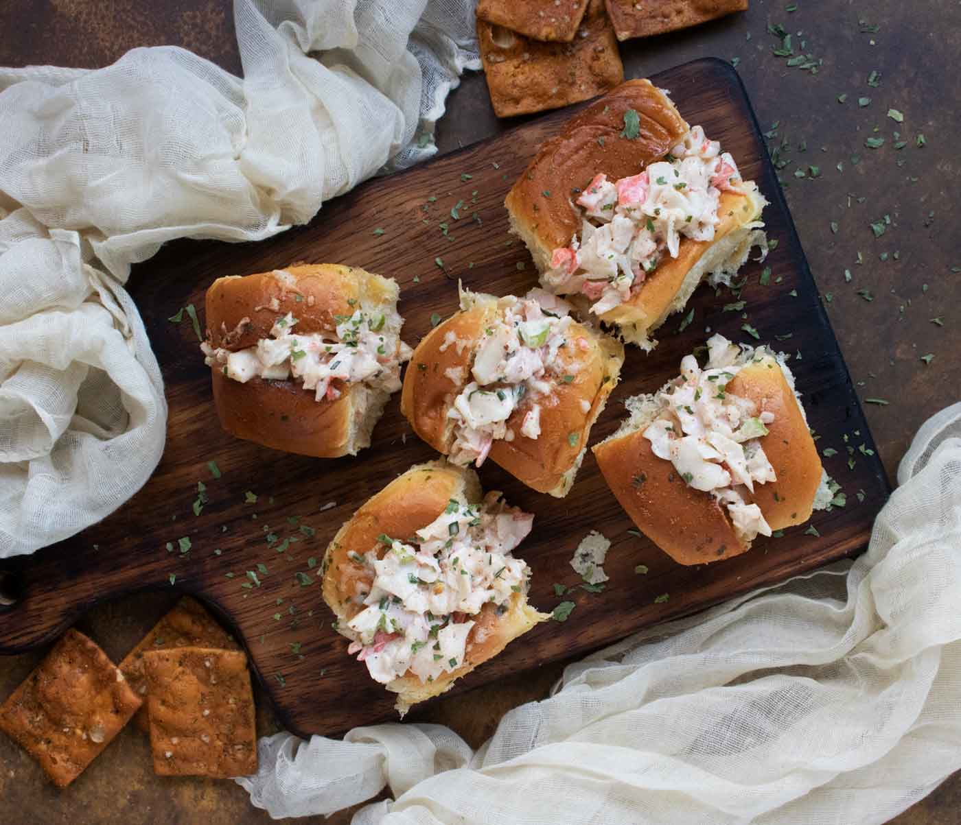 Overhead view of 5 Crab Salad Sliders on a wooden serving board.