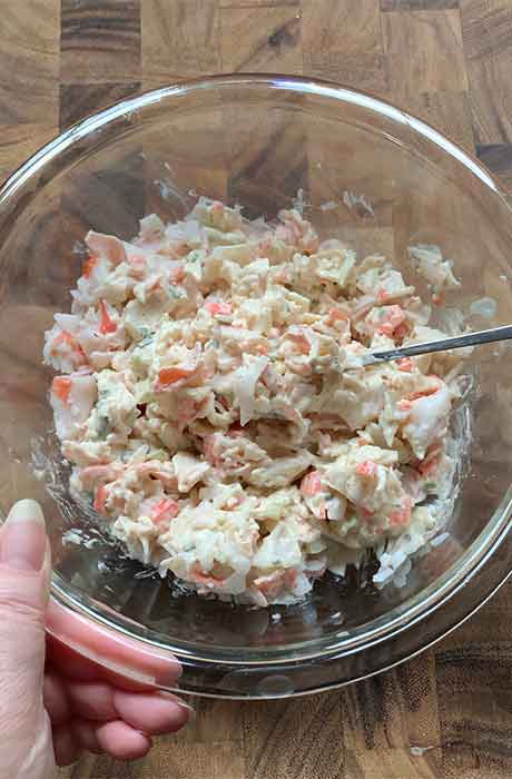Folding the crab/surimi meat into the crab salad dressing.