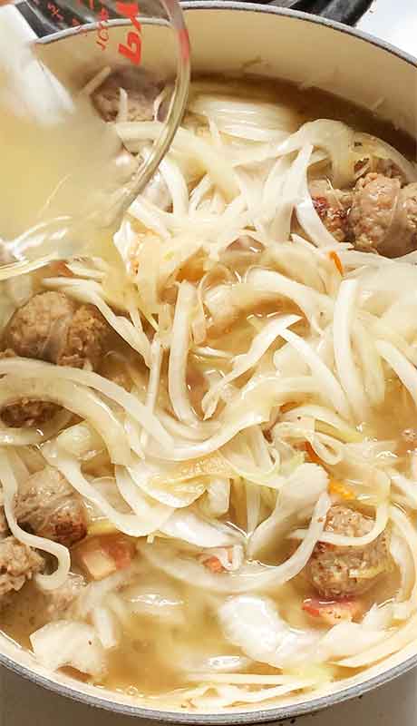 Pouring in the chicken broth to create the base of the stew.