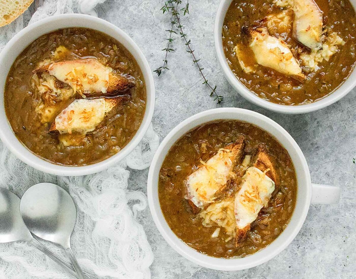Overhead view of 3 bowls of Guinness Onion Soup with cheddar toast points on top.