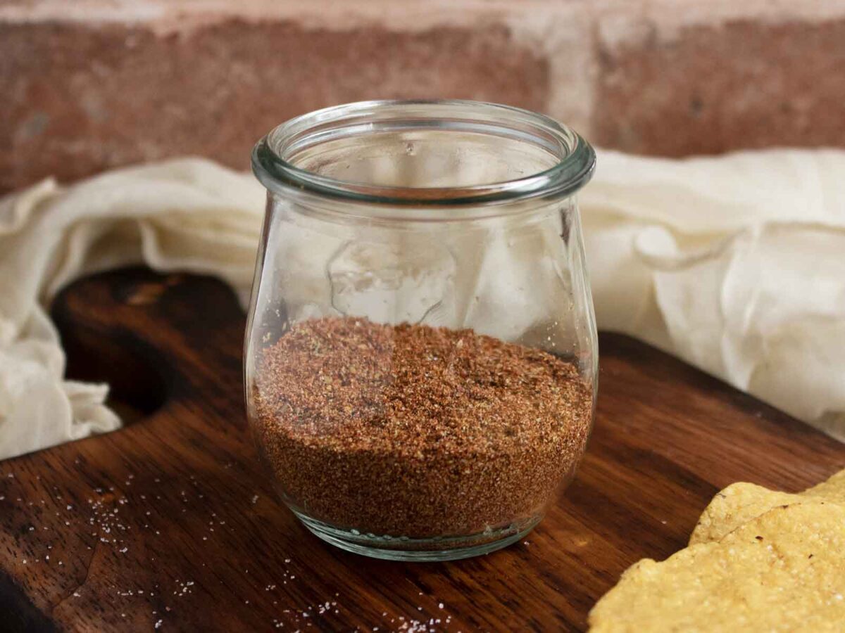 Side view of a jar of Low-Sodium Taco Seasoning, on a wood serving board.