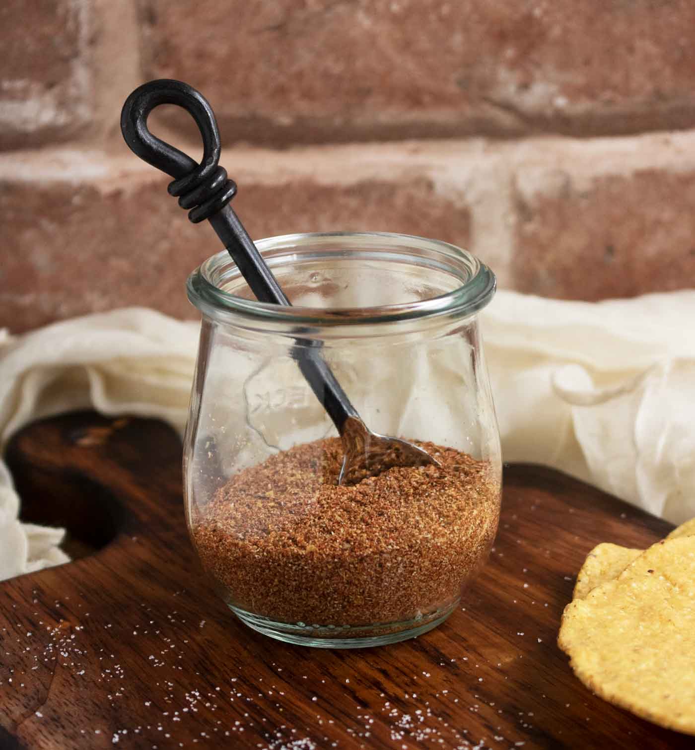 Side view of the low-sodium taco seasoning spice jar with a small spoon inserted.