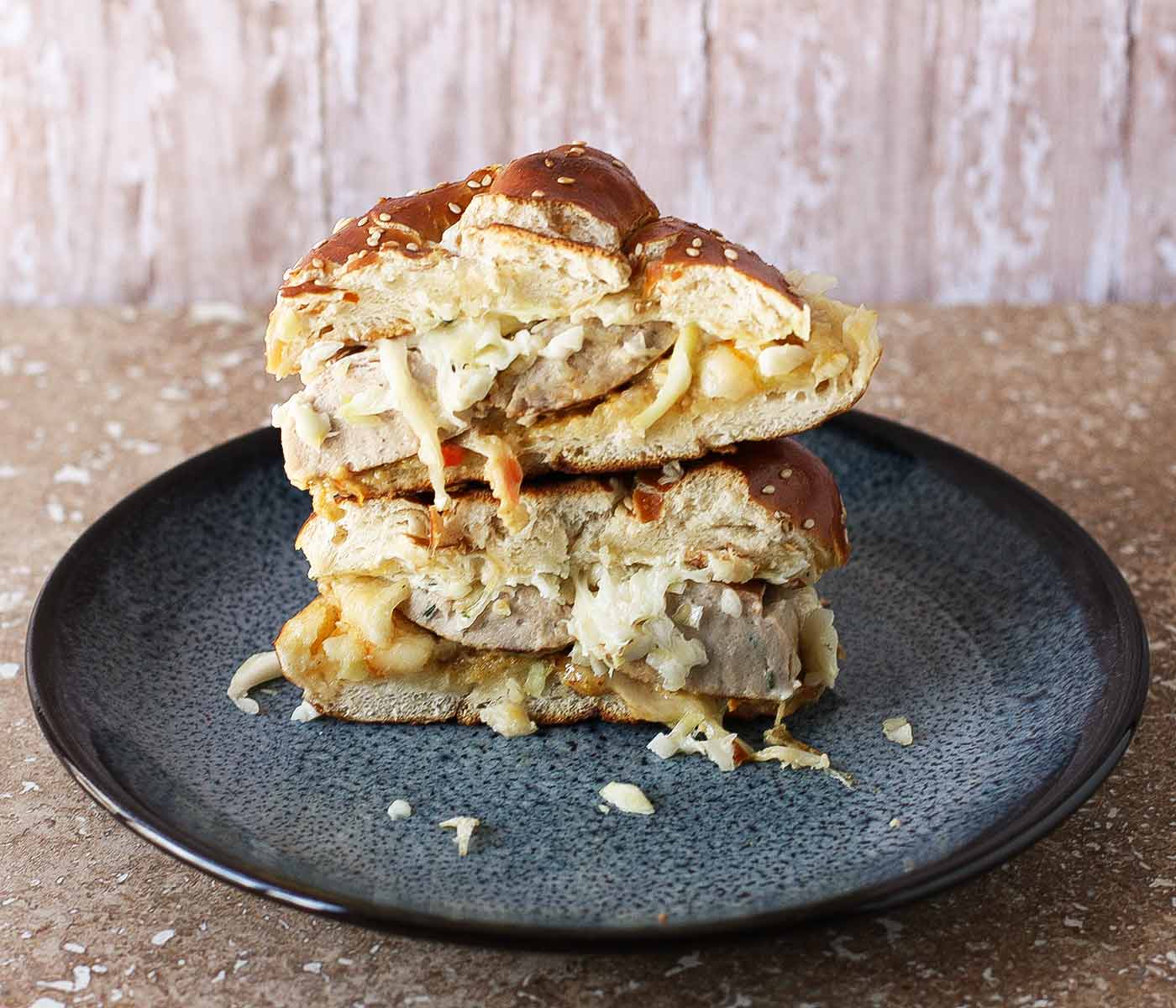 Two stacked halves of a bratwurst grilled cheese sandwich on a blue plate.