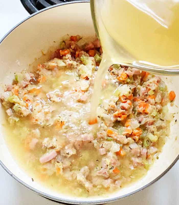 Pouring the chicke broth into the soup.