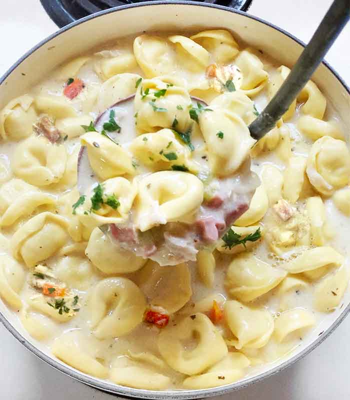 A ladle holding some of the finished soup above the pot.