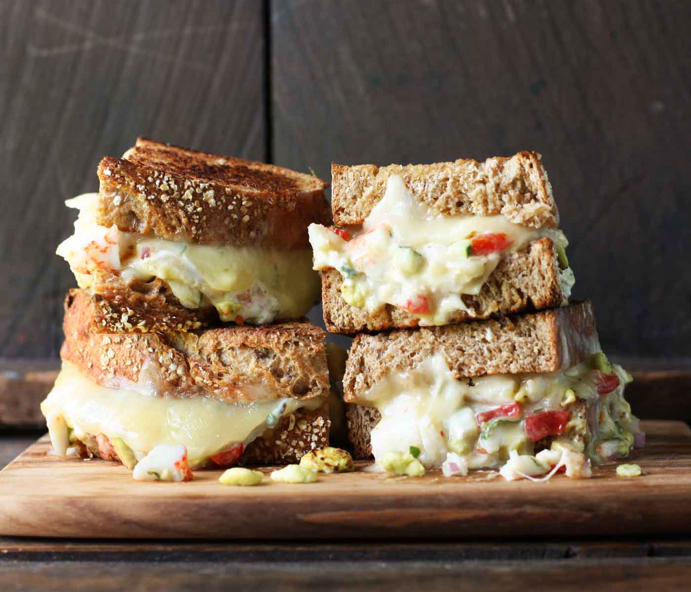 Four halves of two crab salad grilled cheese sandwiches stacked to show off their fillings.