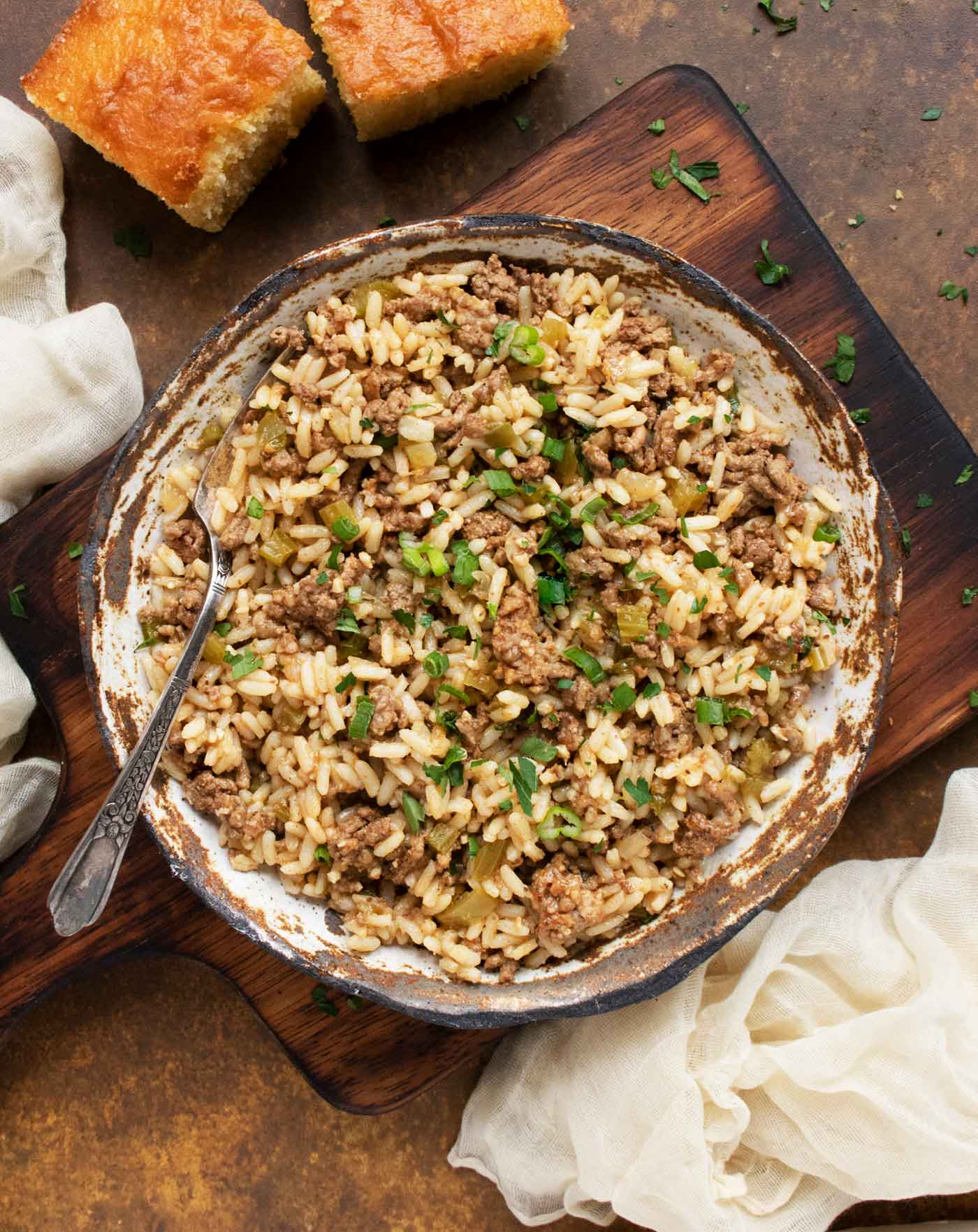 Overhead view of a bowl of Dirty Rice on a small wooden serving board.