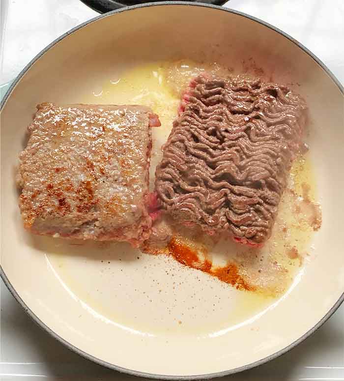 Adding the beef and sausage to the skillet.