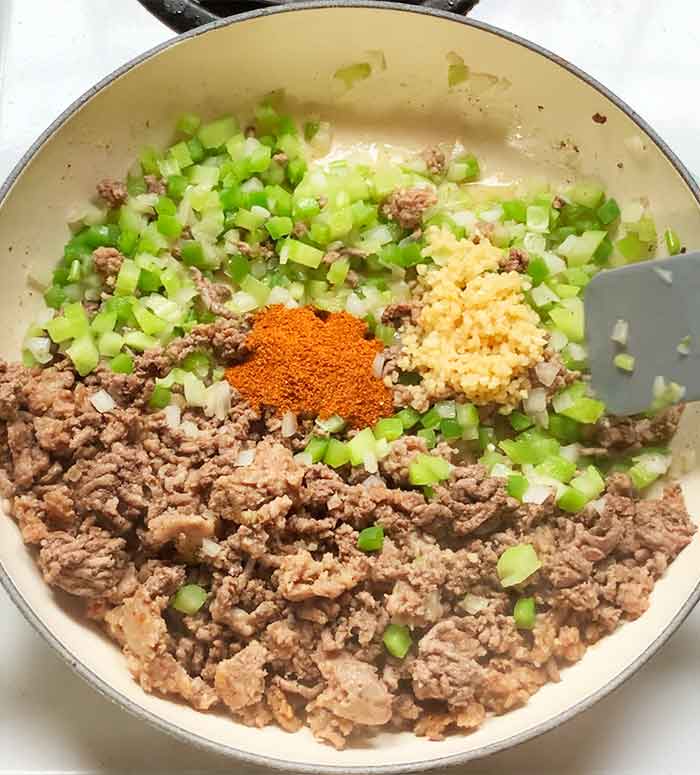 Stirring the garlic and spices into the meat and vegetable mixture.