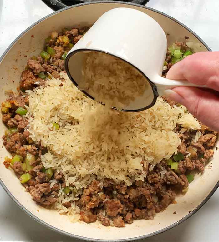 Adding rinsed rice to the skillet.