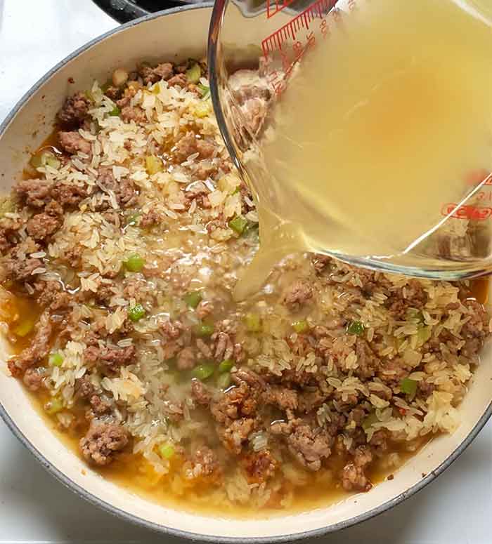 Pouring the broth into the skillet.