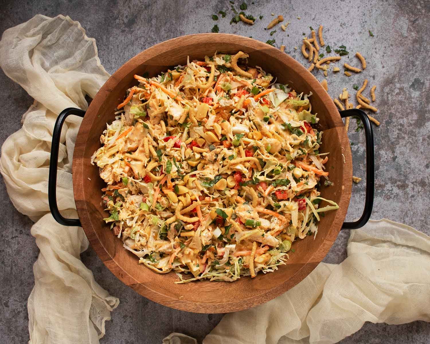 Overhead view of Chili Crisp Chopped Chicken Salad in a wooden salad bowl with metal handles.
