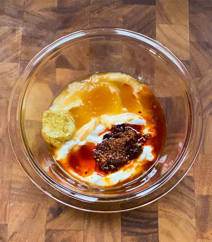 Overhead view of dressing ingredients in a clear, glass bowl.