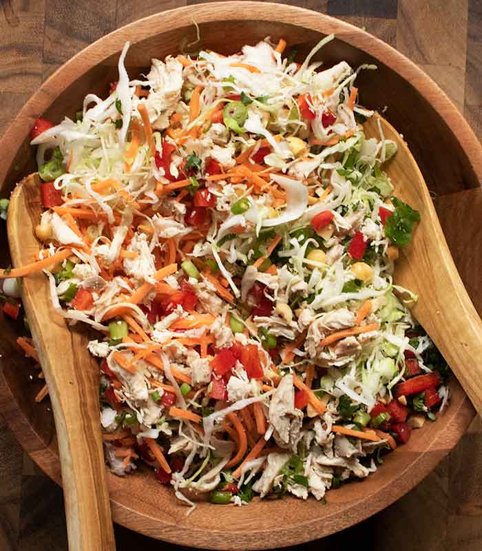 In the process of tossing the salad with wooden salad utensils.