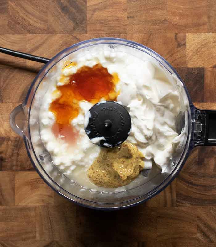 Overhead view of the dressing ingredients in the bowl of a small food chopper.