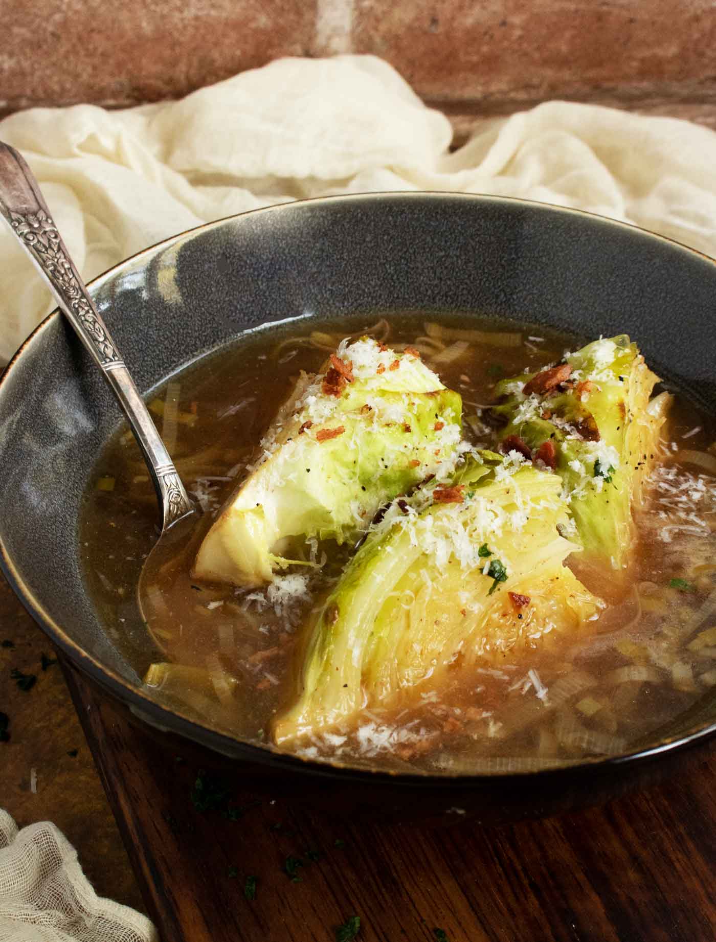 Side-angled view of a soup bowl with the broth and roasted cabbage.