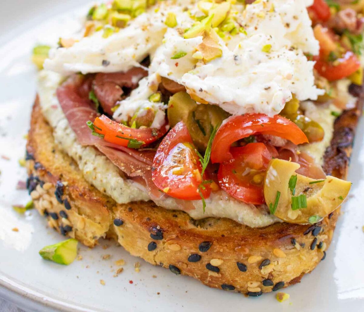 Side-angled view of Mediterranean Burrata Fried Toast on a white plate.