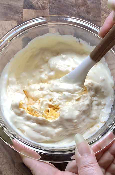 Mixing the mayo and sour cream with the smashed egg yolks.