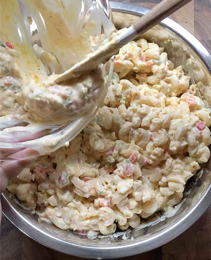 Pouring the dressing over the pasta and egg whites.