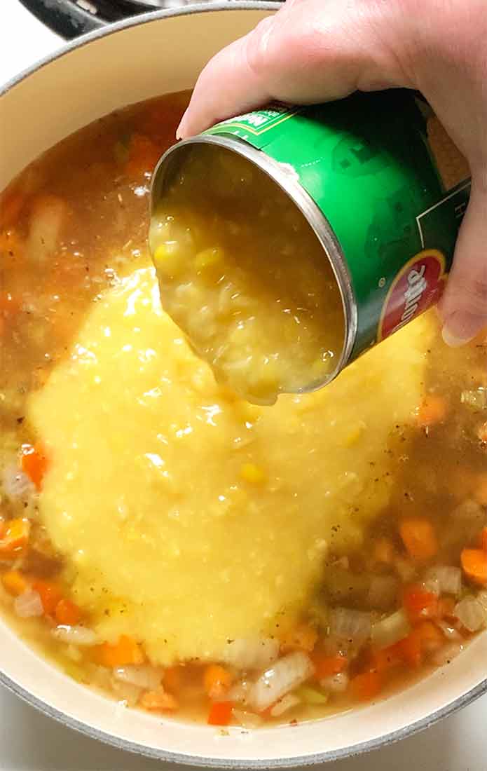 Adding the chicken broth and the creamed corn to the pot.