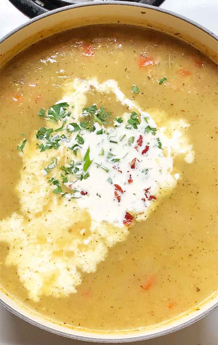Finishing the soup with heavy cream, the crisped bacon, and herbs.