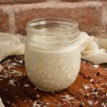 Close up of a glass jar filled with Caesar dressing.