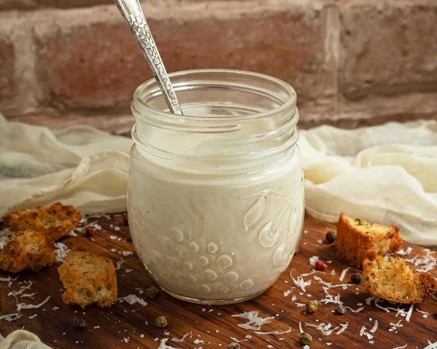Close-up of Easy Caesar Dressing in a glass jar with a spoon.