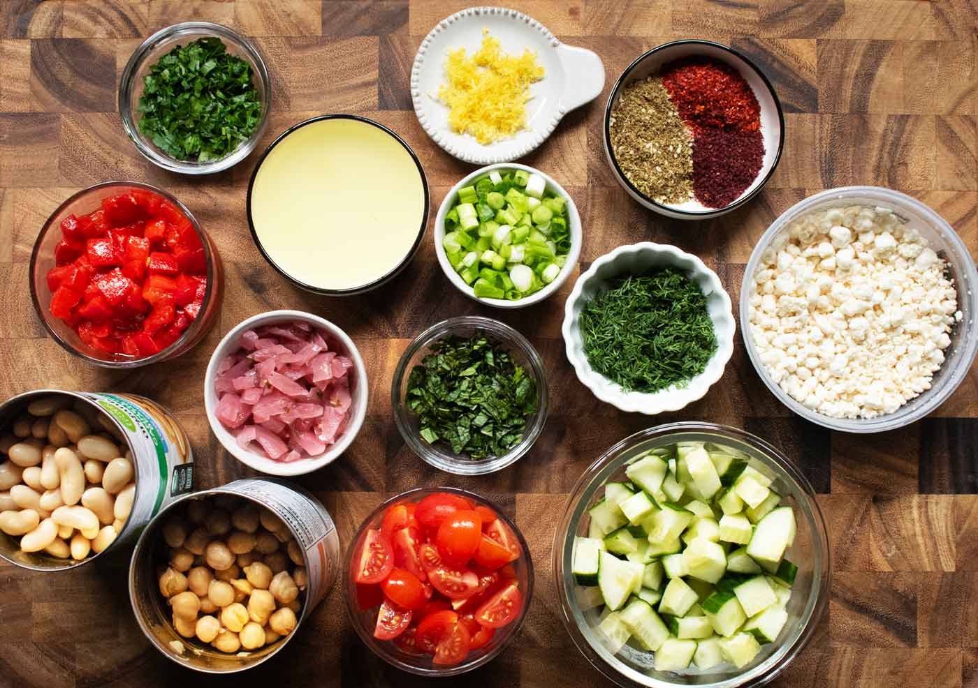 Ingredients for Mediterranean Bean Soup measured out into bowls and arranged on a wooden board.