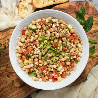 Overhead view of Mediterranean Bean Salad on a wooden serving board.